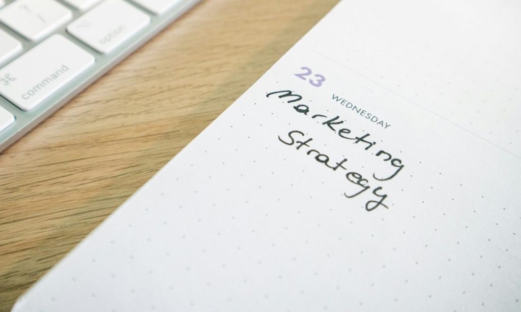 Desk with a keyboard and a planner with the words Marketing Strategy on it
